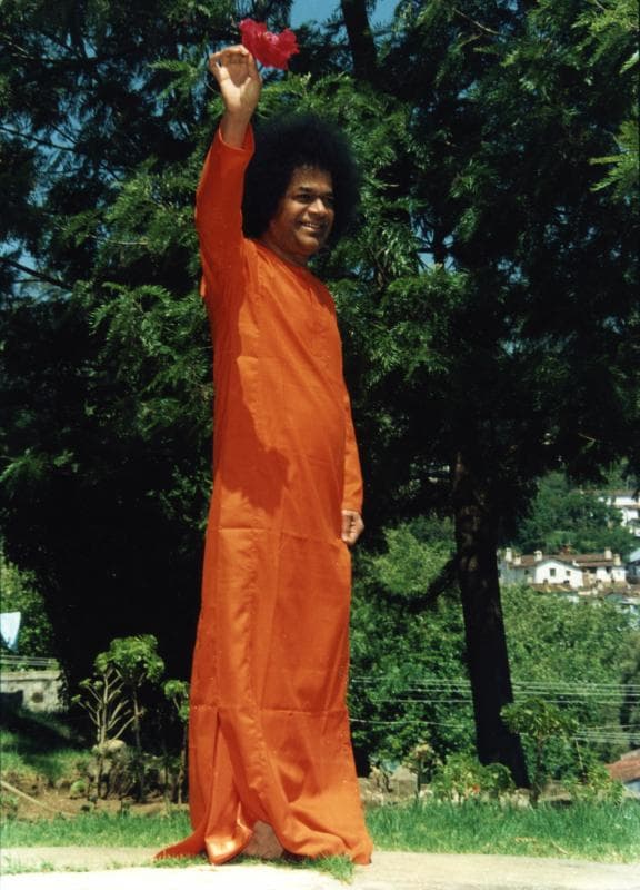 Sri Sathya Sai Baba with children offering flowers